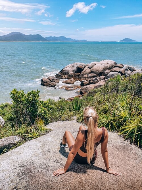 A girl sitting on a rock overlooking the natural pools of Barra da Lagoa in Florianopolis, the last destination of our 10 days in Brazil itinerary