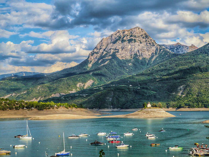 small boats anchored in Lac de Serre-Ponçon, one of the most famous lakes in France and a popular summer holiday destination in the Alpes region