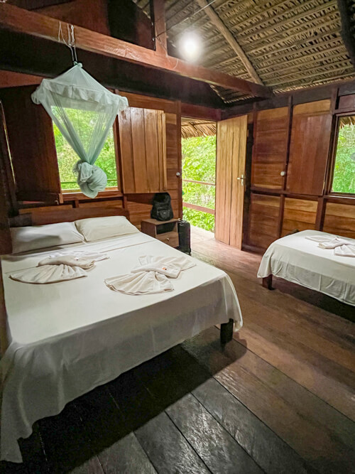 Our simple bungalow with wooden walls and floors and two beds with mosquito nets.