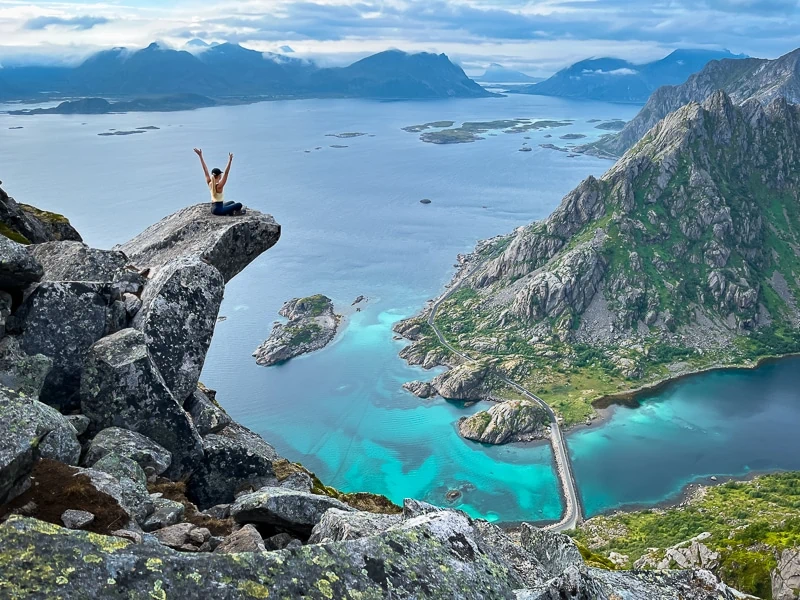 Me sitting on a slab of rock protruding from a mountainside at Torsketunga, one of the top hikes in Lofoten.