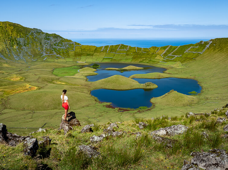 Me standing on a rock on the rim of the lush green Caldeirao crater overlooking the blue lagoons in the center of the crater