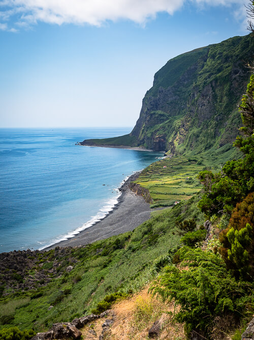 The rocky beach of Faja de Lopo Vaz surrounded by towering cliffs covered with vegetation 