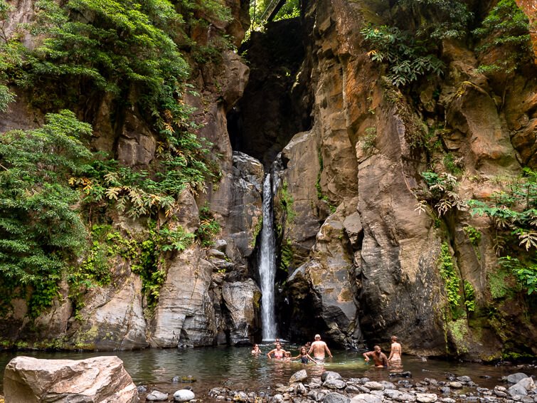 People swimming in the natural pool of Salto do Cabrito waterfall, one of the most popular waterfalls on Sao Miguel.