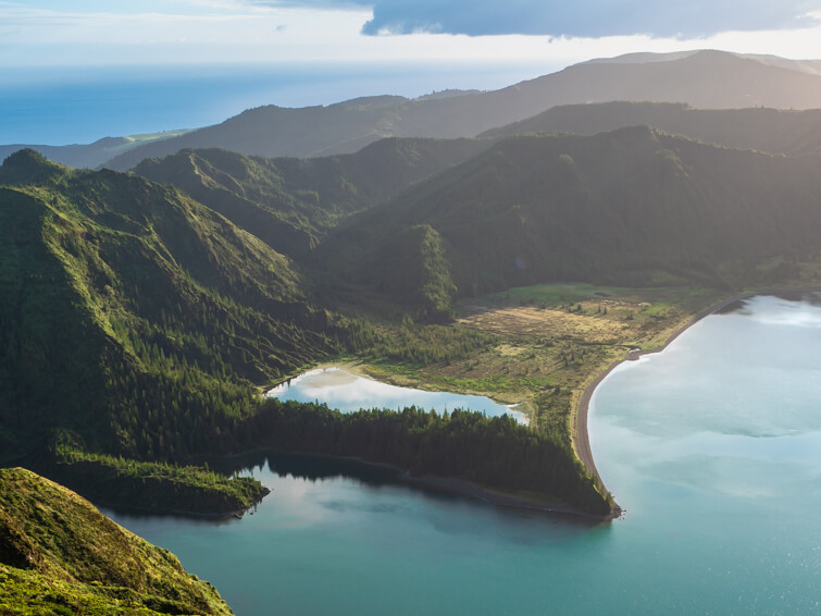 The jagged shoreline of  Lagoa do Fogo surrounded by green mountains.