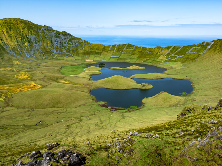 The large crater of Caldeirao Volcano in Corvo with its steep green walls and deep blue crater lakes.