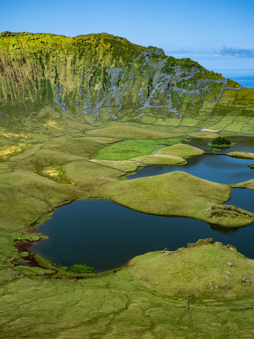 Blue lakes surrounded by green pastures at the bottom of Caldeirao Volcano crater on Corvo Island.