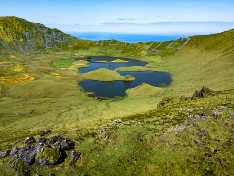 The large green crater of Caldeirao Volcano with its pastures, dark blue lakes and steep walls.