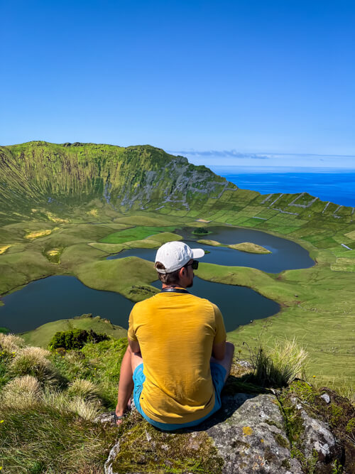 My husband sitting on a rock, enjoying the view of the lakes and steep walls of Caldeirao Volcano.