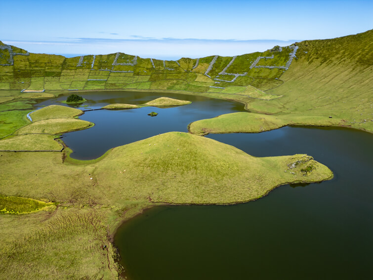 Blue lakes and rolling green hills in the crater of Caldeirao Volcano.