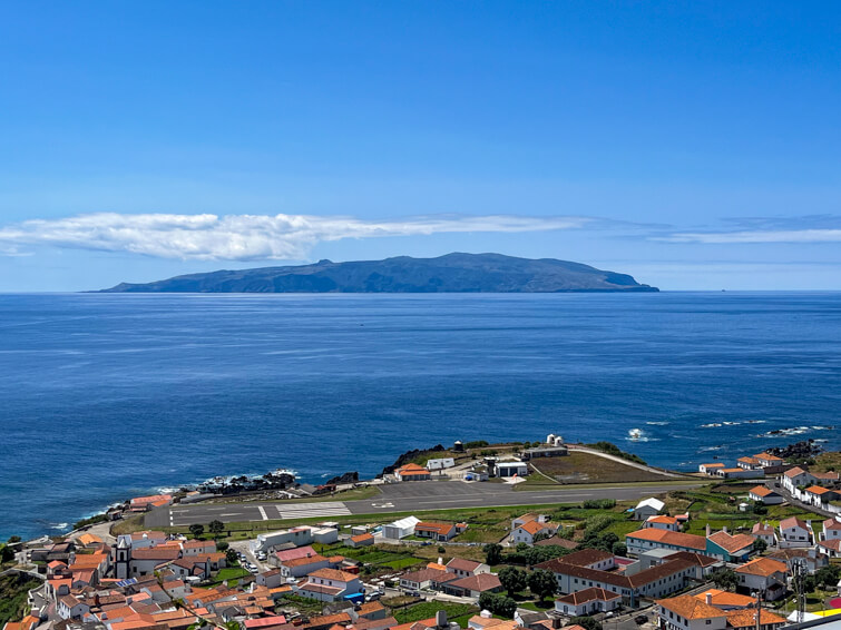 A view over Vila do Corvo village with its white houses with terracotta roofs and the island of Flores on the horizon.