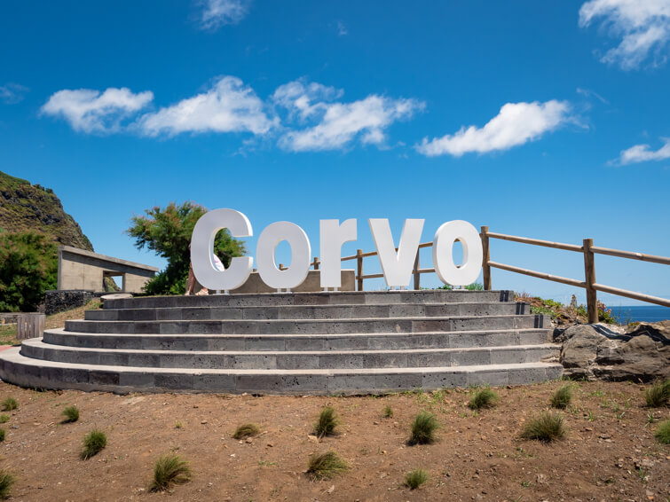 A large white sign stating Corvo with blue skies in the background.