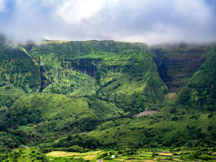 Steep mountains covered with vibrant green vegetation and small waterfalls on the west coast of Flores.