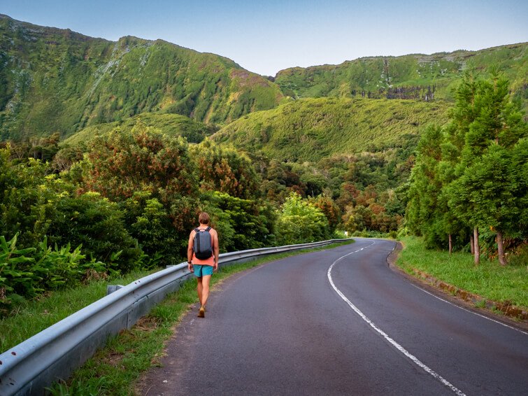 My husband walking along a scenic road on the west coast of Flores with green mountains in the background.