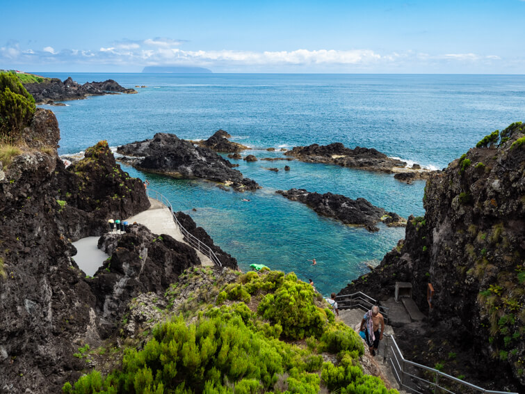 Natural pools with turquoise water surrounded by black volcanic rock formations in Santa Cruz das Flores.