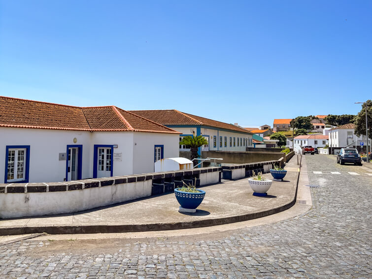 A cobblestone street lined with traditional Azorean-style white buildings in Vila do Corvo. 